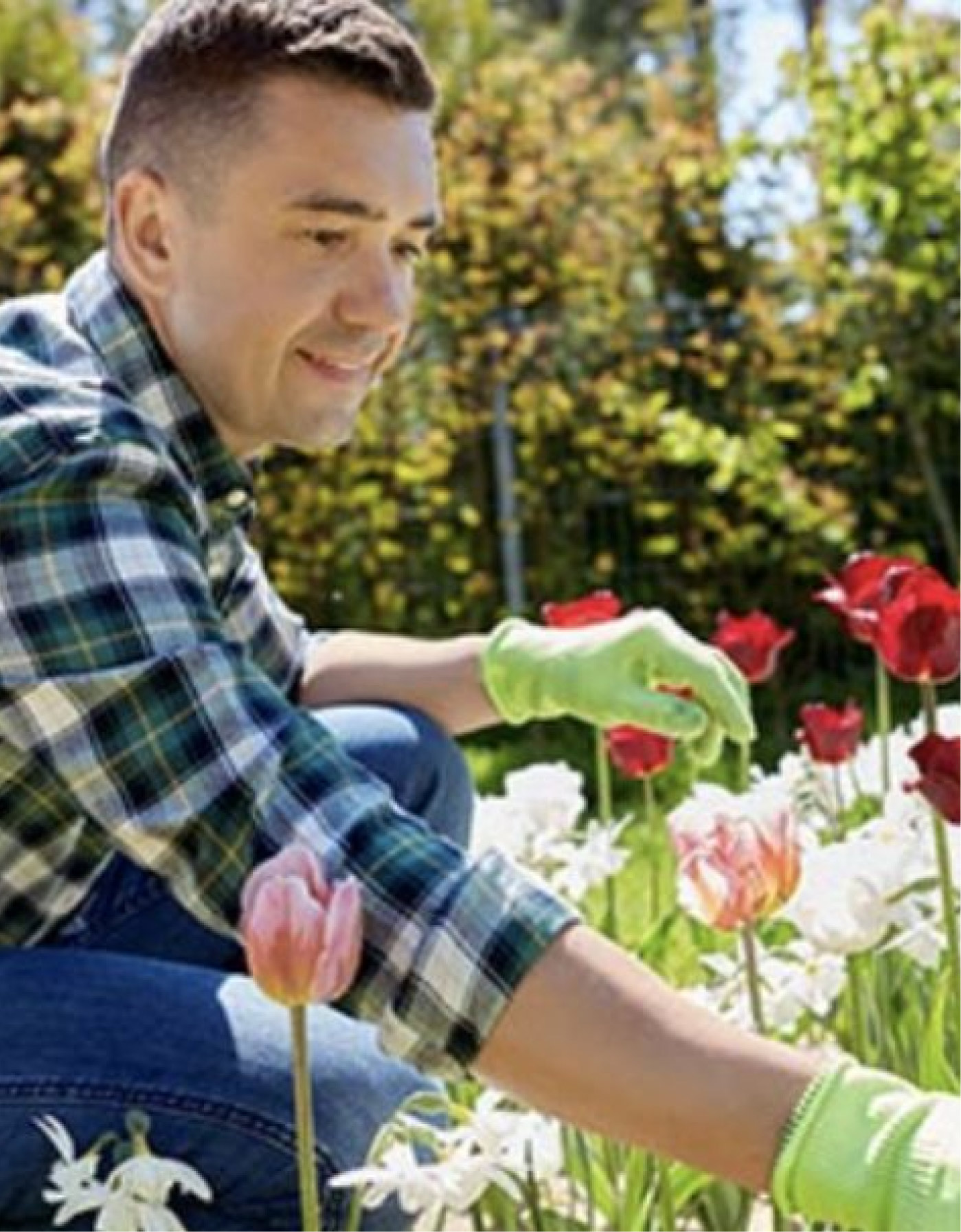 Un uomo con camicia a scacchi &egrave; accovacciato in un prato di fiori